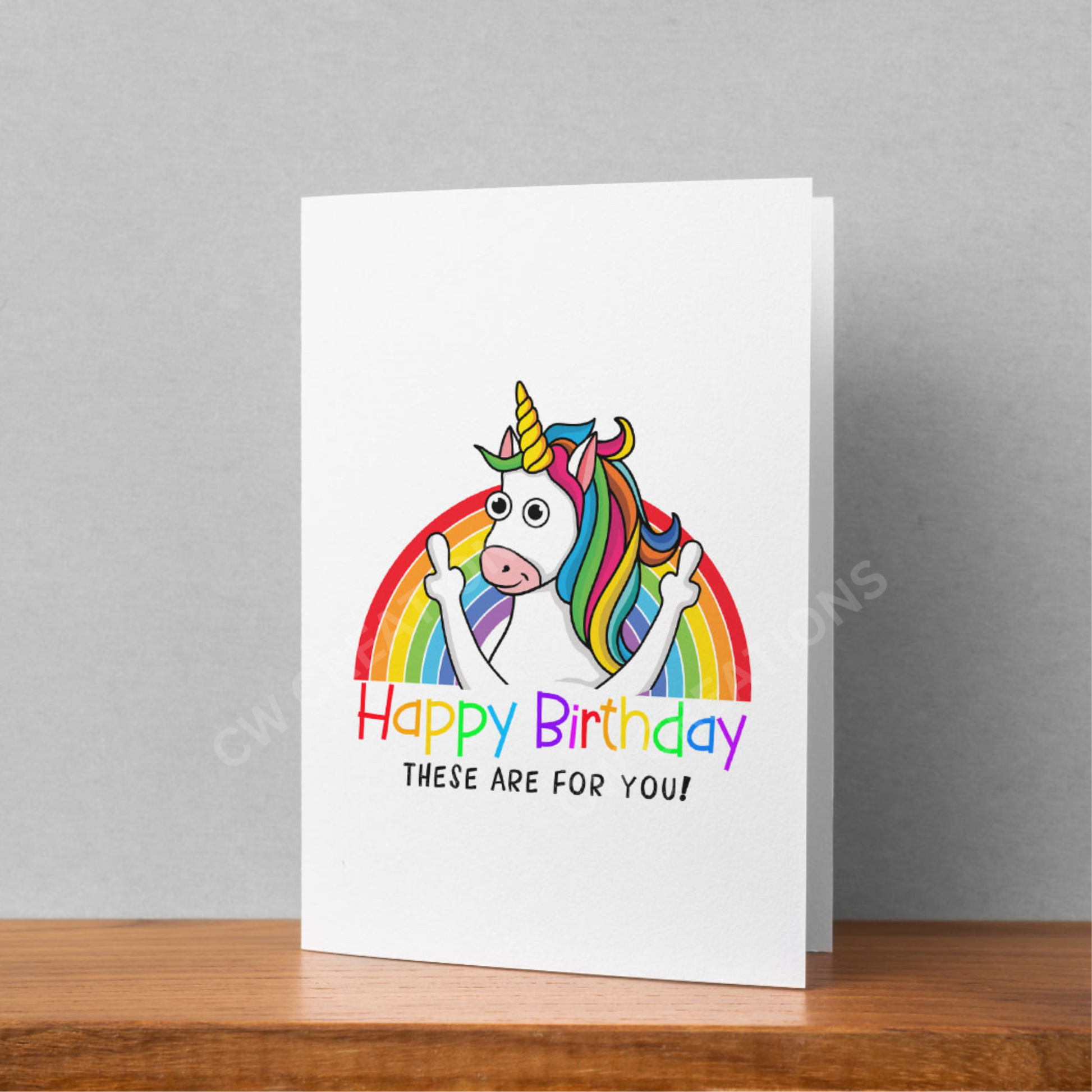 White card with bright colours a unicorn standing in front of rainbow sticking middle fingers up. Reading the words Happy Birthday These Are For You!