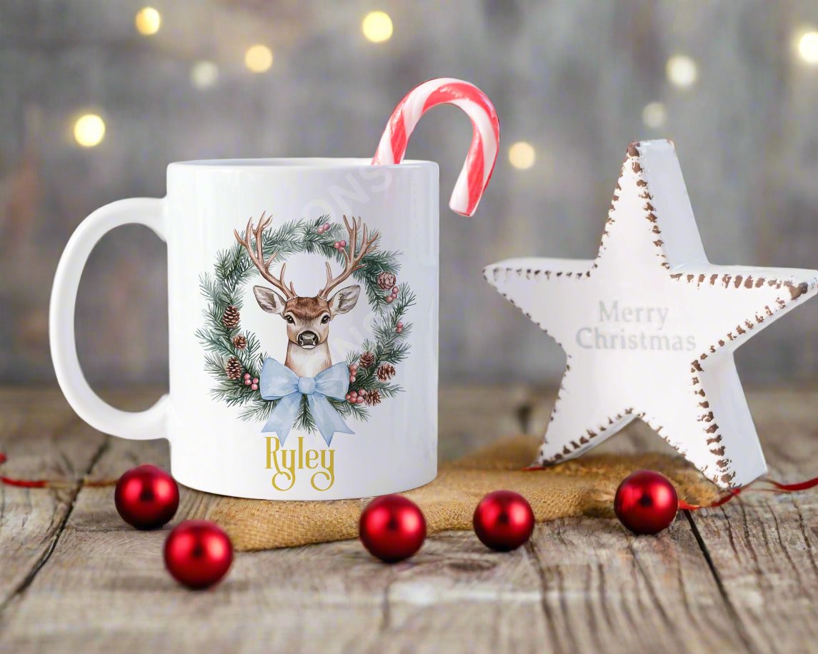 A festive Christmas mug featuring a reindeer design surrounded by a decorative wreath.