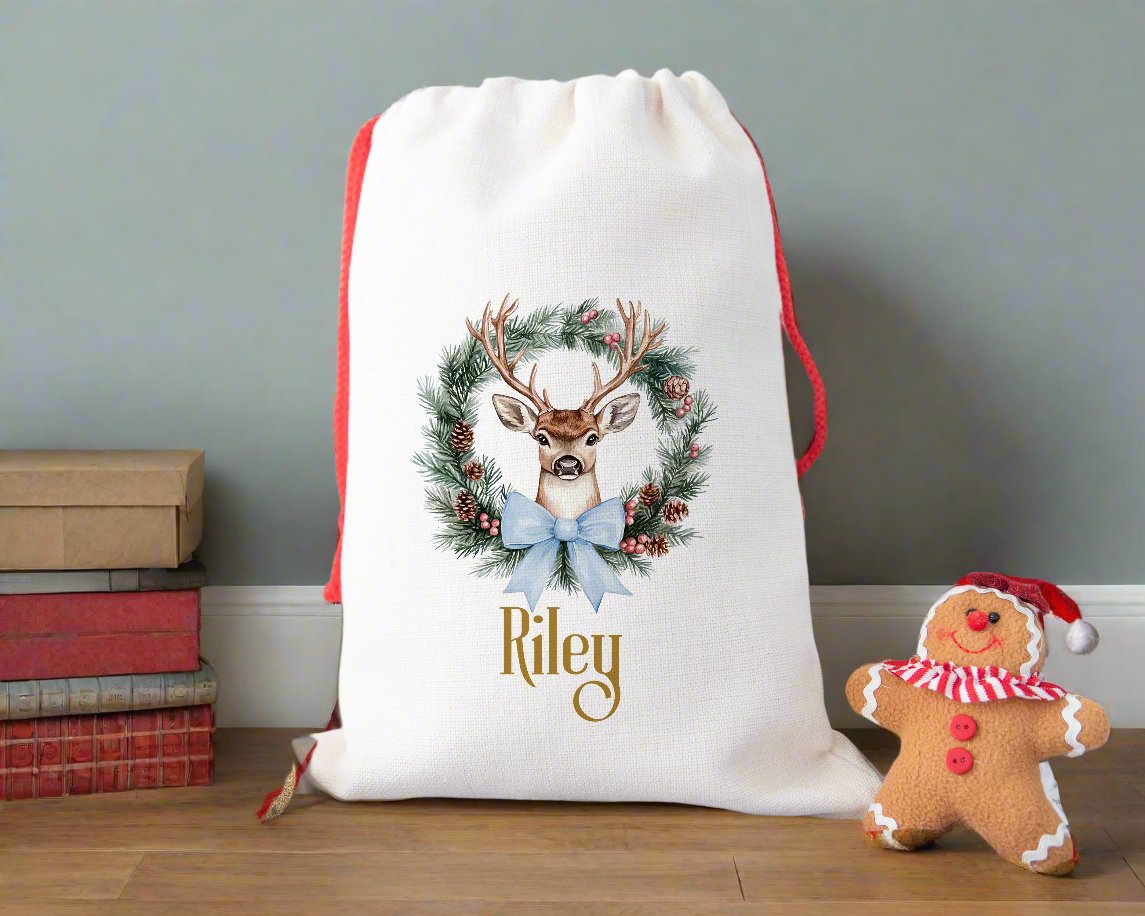 A linen Christmas sack with a Reindeer Wreath with a blue ribbon personalised with a name