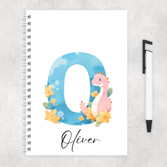 A white notebook with the letter O and a graphic of a dinosaur and flowers.