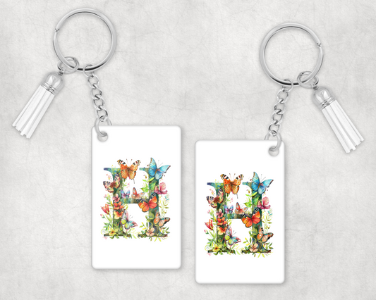 A white keyring with the letter H covered in flowers and butterflies