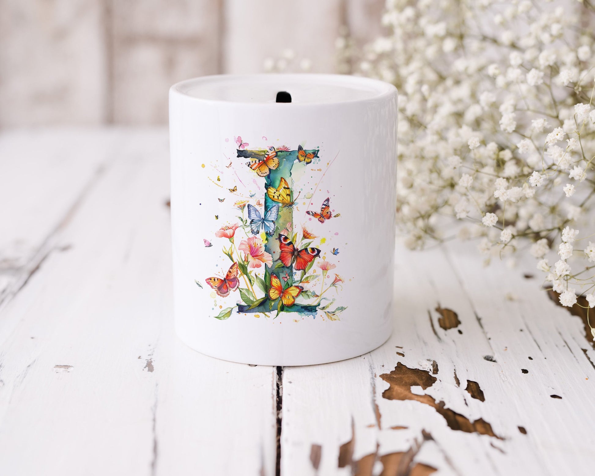 A white money box with the letter I with flowers and butterflies.