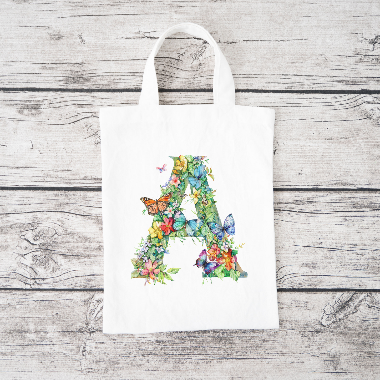 A white bag with the capital letter A covered in flowers and butterflies.