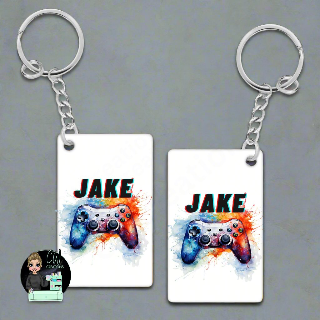 A white MDF keyring with a gaming controllers splashed in paint.