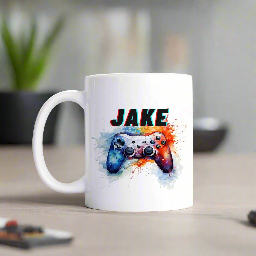 A white mug with a gaming controller on splashes of paint personalised with a name.