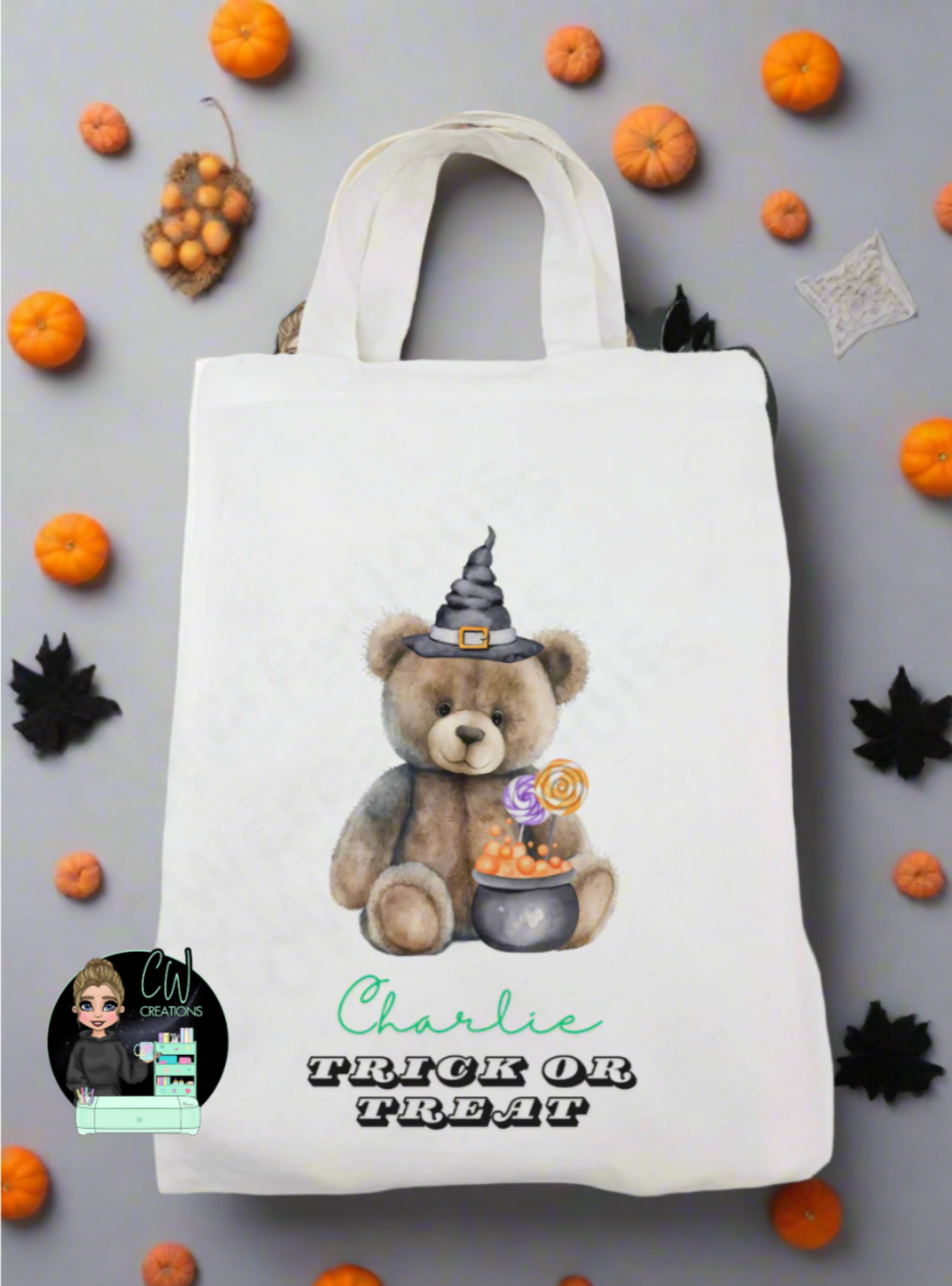 A white bag with a bear wearing a witches hat infront of a cauldron.