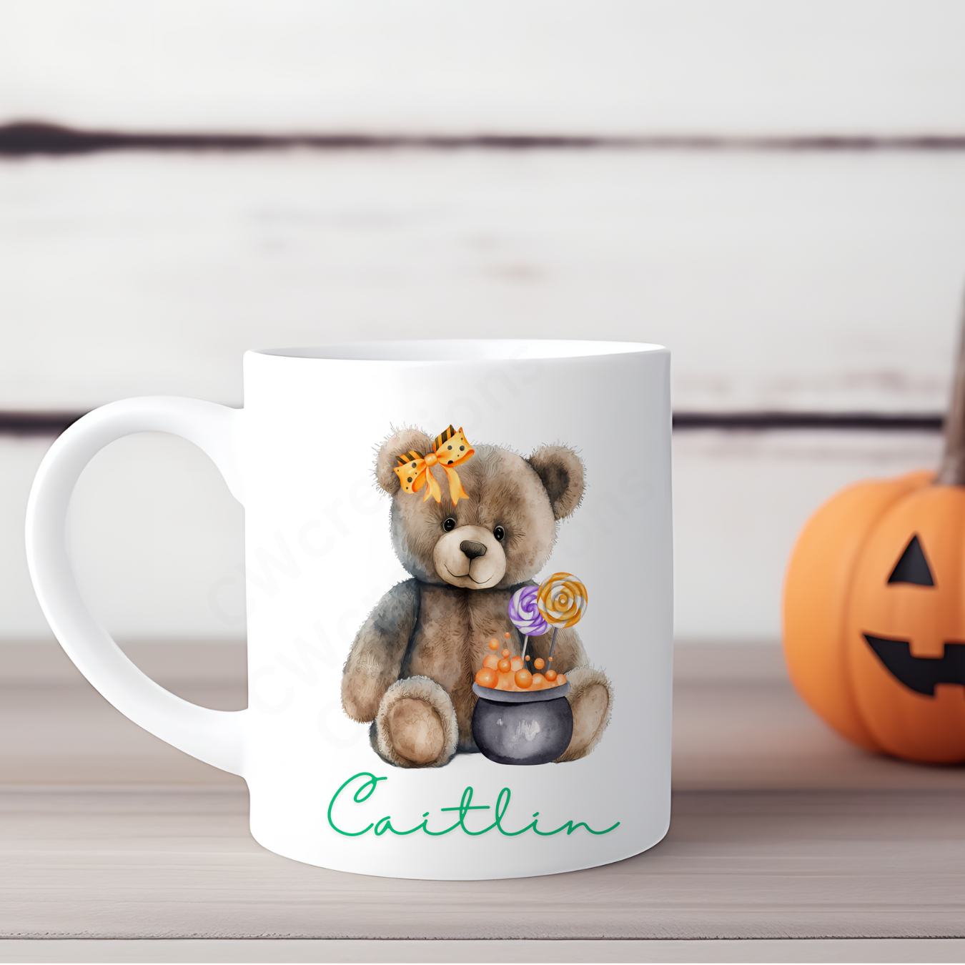 A white mug with a Teddy wearing a orange bow and cauldron personalised with a childs name.