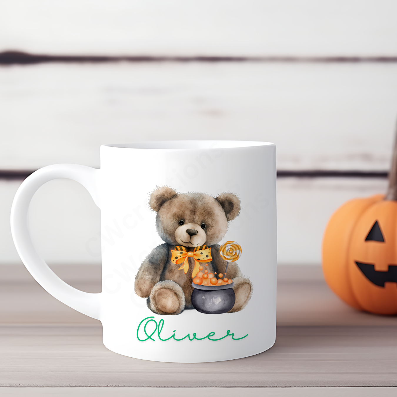 A white mug with a Teddy wearing a orange bow and cauldron personalised with a childs name.