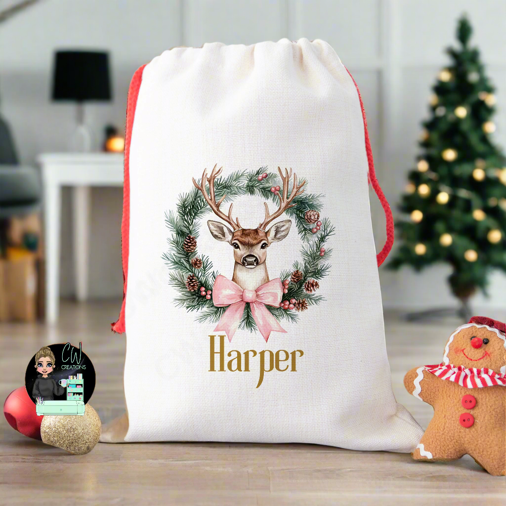 A linen Christmas sack with a Reindeer Wreath with a blue ribbon personalised with a name