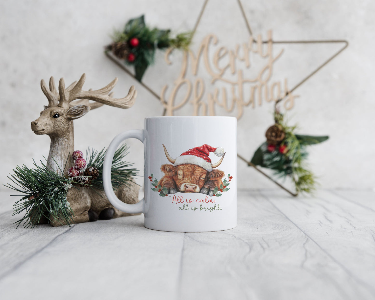 A white mug with a sleeping highland cow with words All is calm all is bright.