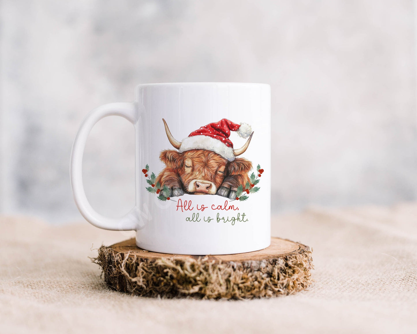 A white mug with a sleeping highland cow with words All is calm all is bright.