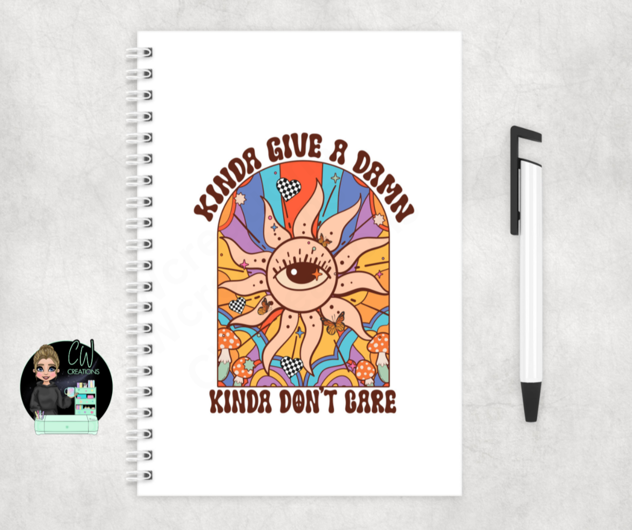 A notebook with words kinda give a damn kinda don’t care with a colourful graphic of the sun and an eye