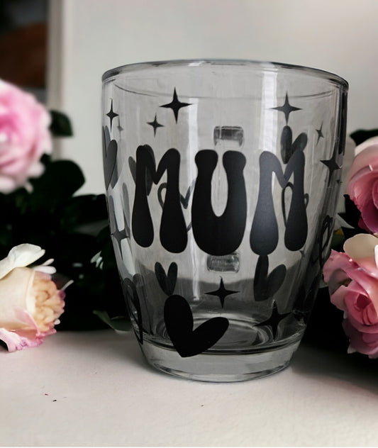 A glass mug with hearts and stars and the words mum in black vinyl.