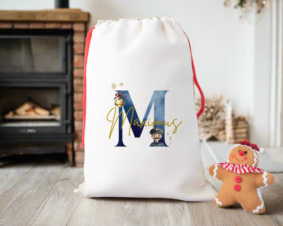 A linen Christmas sack personalised with a initial and a name with the image of a bell and a train conductor.