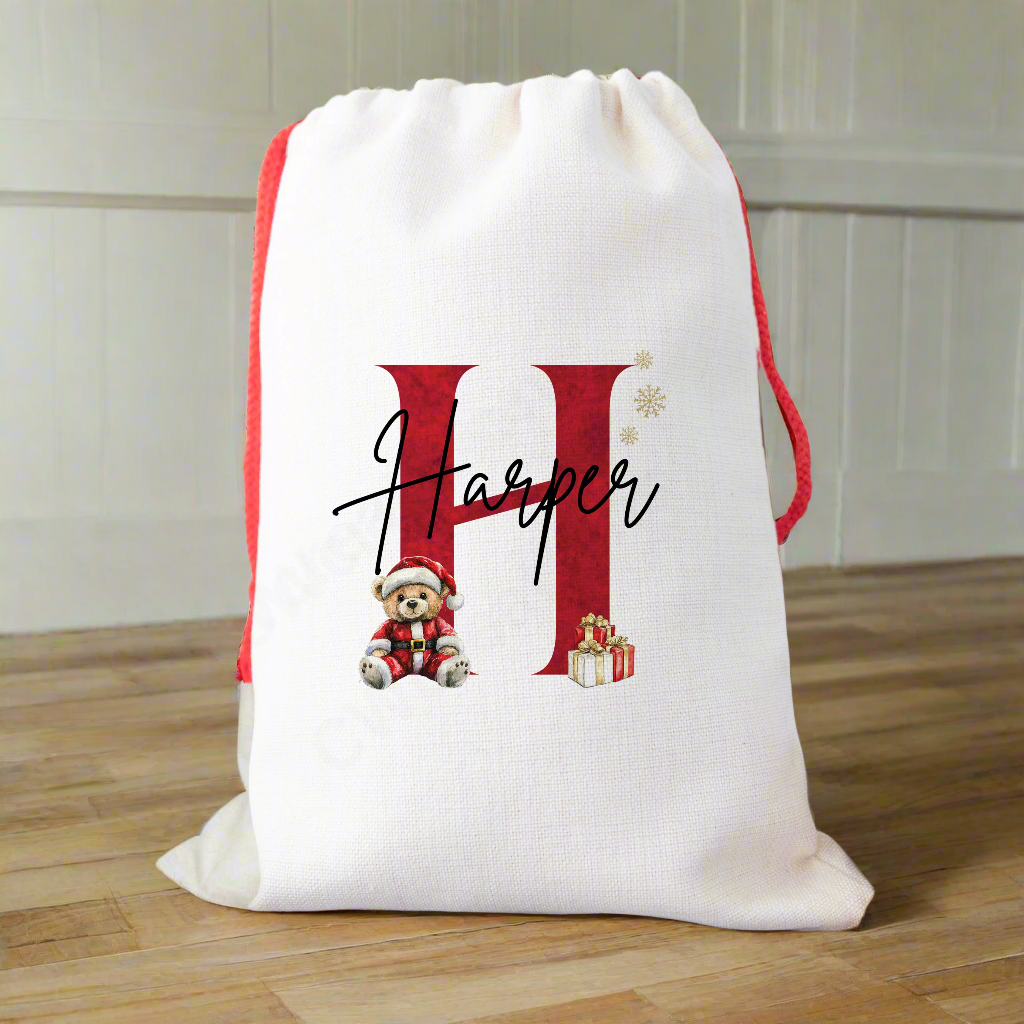 A linen Christmas sack Personalised with a initial and a name with a cute Christmas teddy and presents graphic