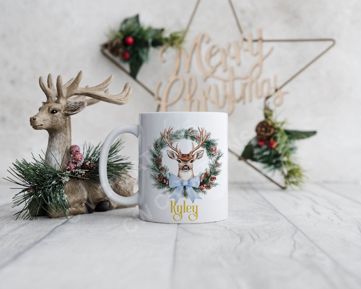 A festive Christmas mug featuring a reindeer design surrounded by a decorative wreath.