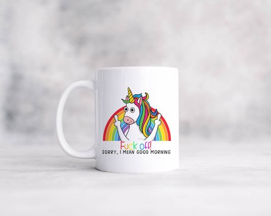 A white mug with a unicorn standing infront of a rainbow with the words F*ck off! Sorry, I Mean Good Morning.