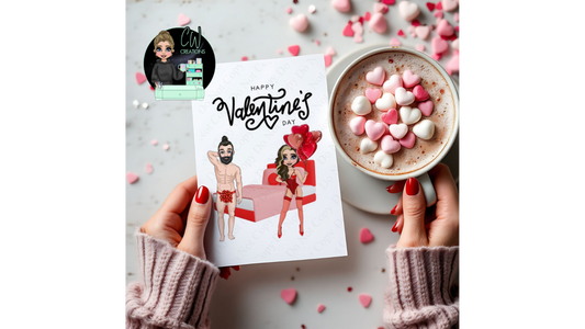 A white card with the words Happy Valentine's Day at the top, with an cartoon Image of a male with dark top bun and beard wearing a red bow and a female cartoon image with brown and blonde hair, wearing red lingerie stood in front of bed with a red headboard pink throw. The card is being held by female holding a cup of hot chocolate and  love heart shaped marshmallows.